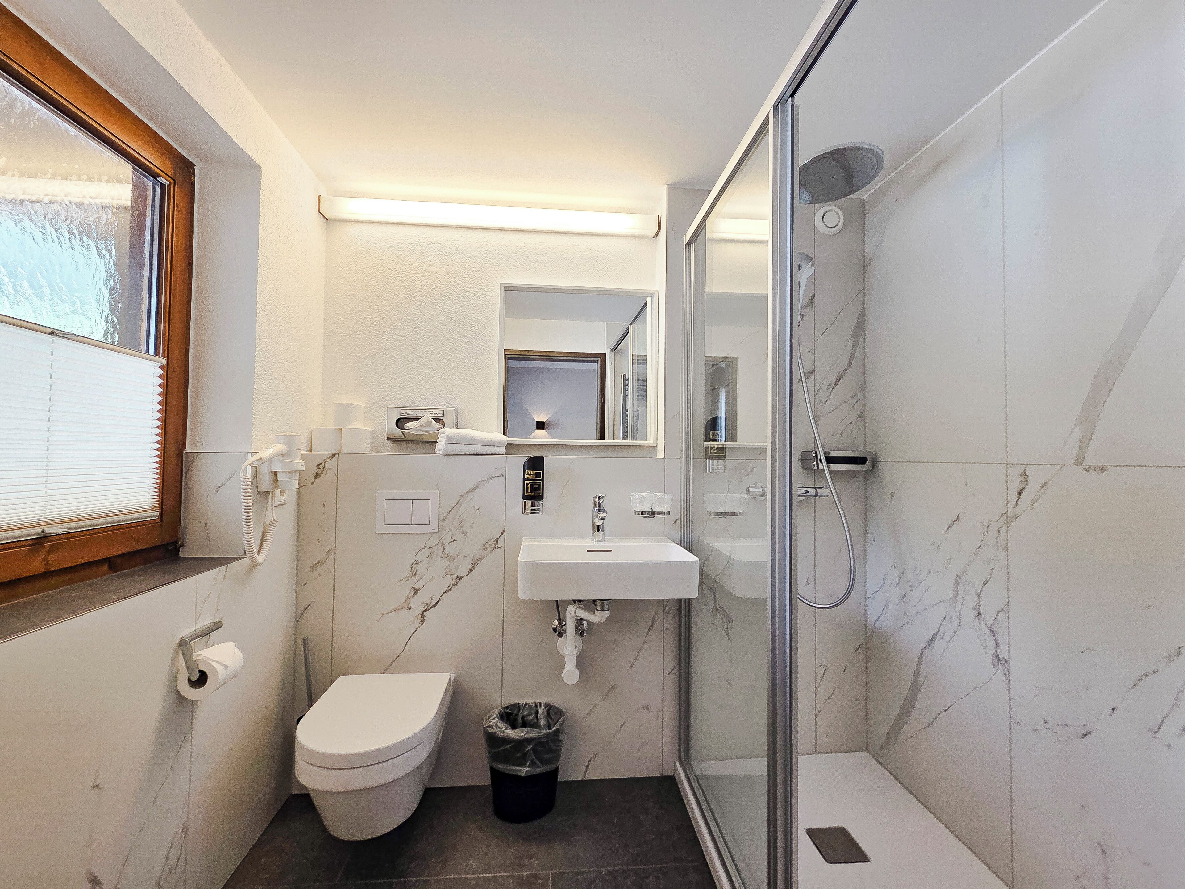 Een kleine badkamer met toilet, wastafel en douche.