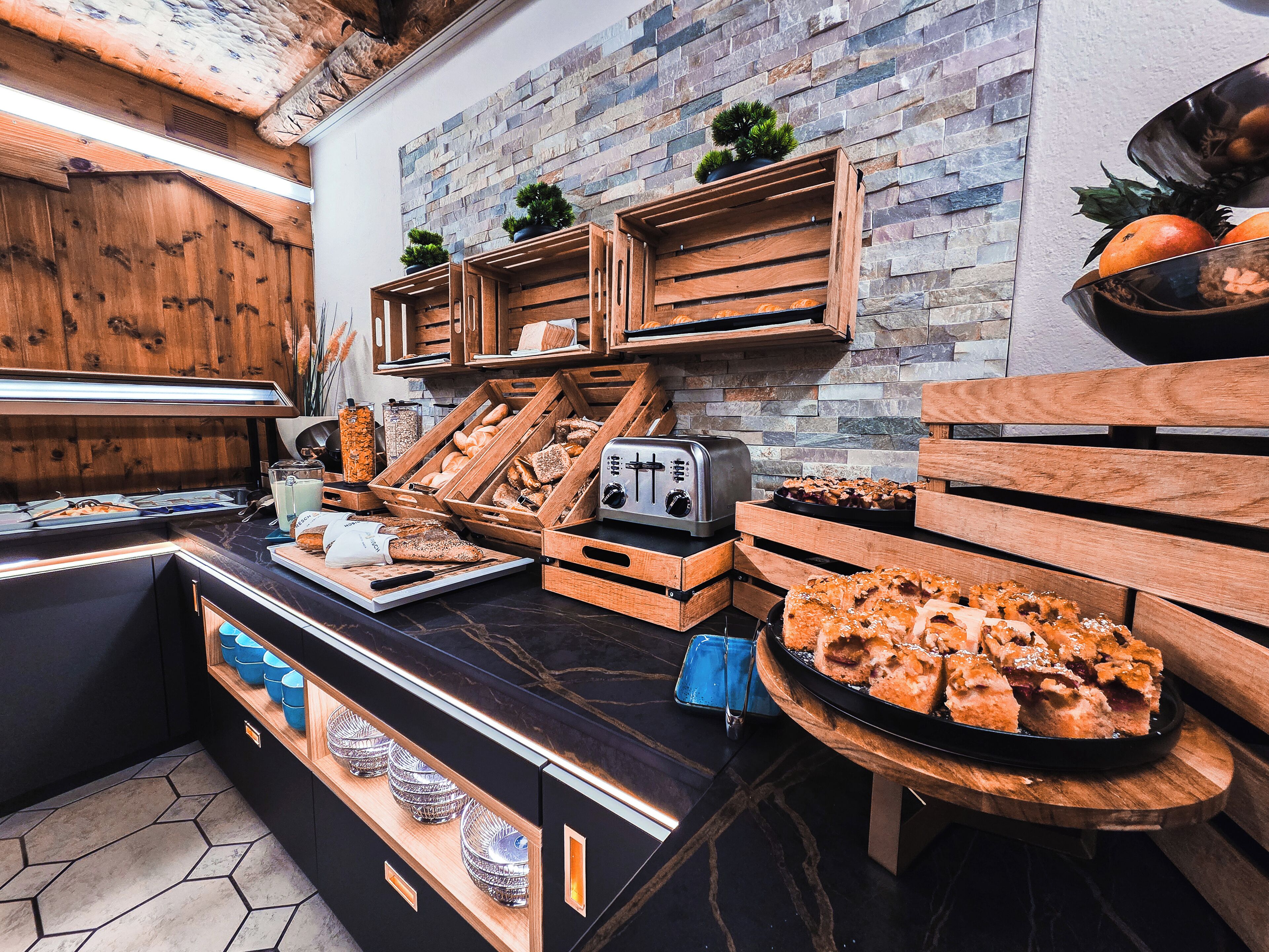 A breakfast buffet with various baked goods and pastries displayed in wooden crates and trays.