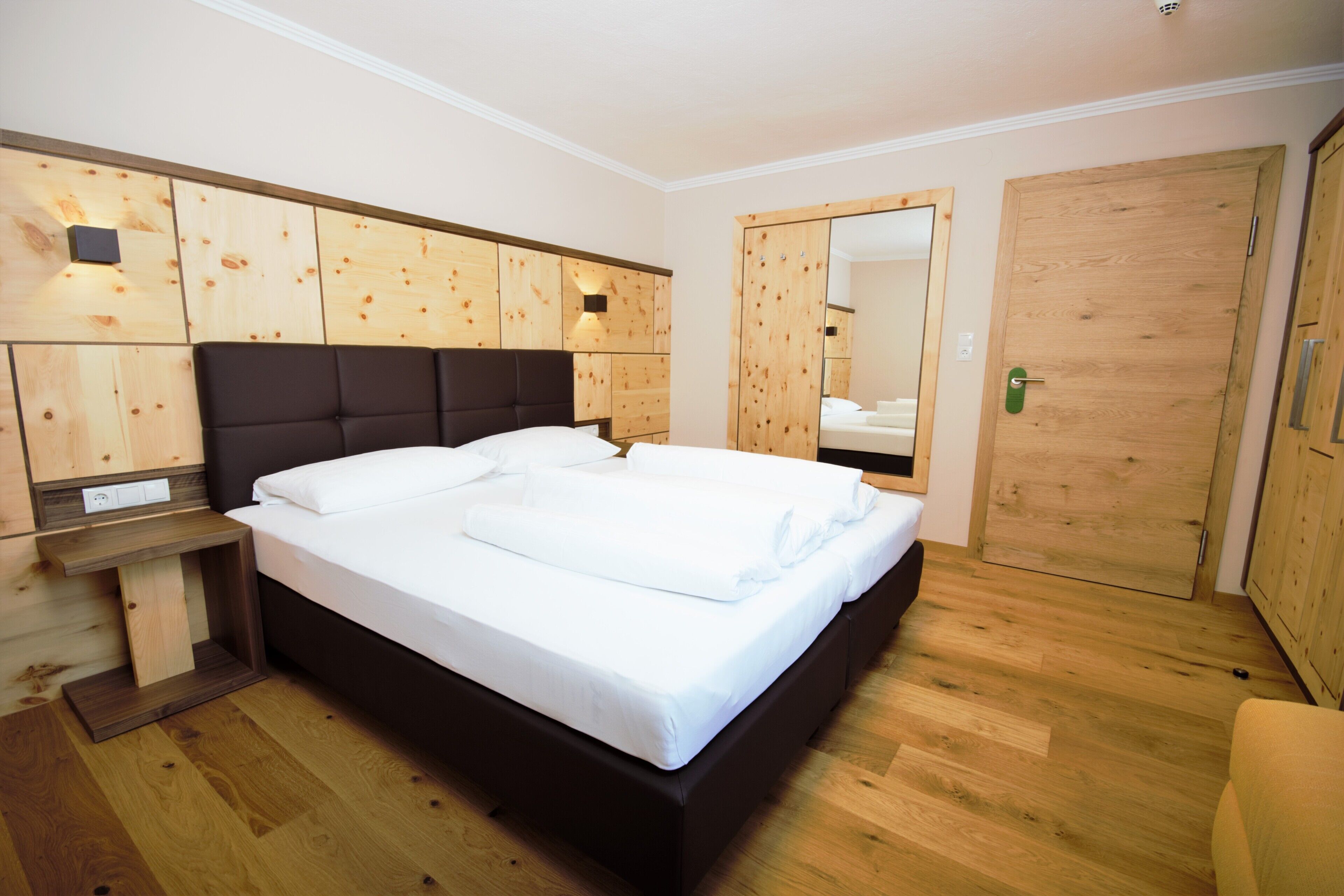 Un dormitorio moderno con una cama grande, paneles de madera, un armario empotrado y un espejo.