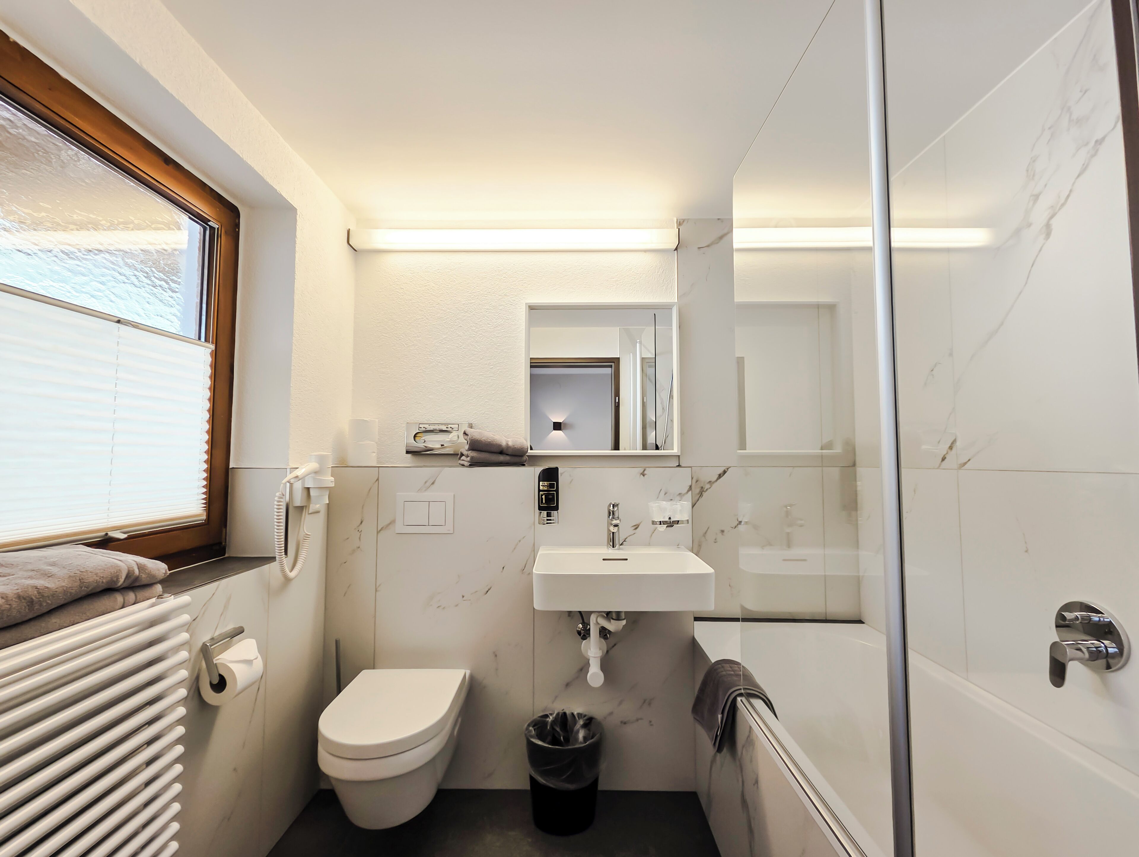 A compact bathroom with a toilet, sink, and a glass shower enclosure.