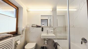 Ein kleines Badezimmer mit Toilette, Waschbecken und einer Duschkabine aus Glas.
