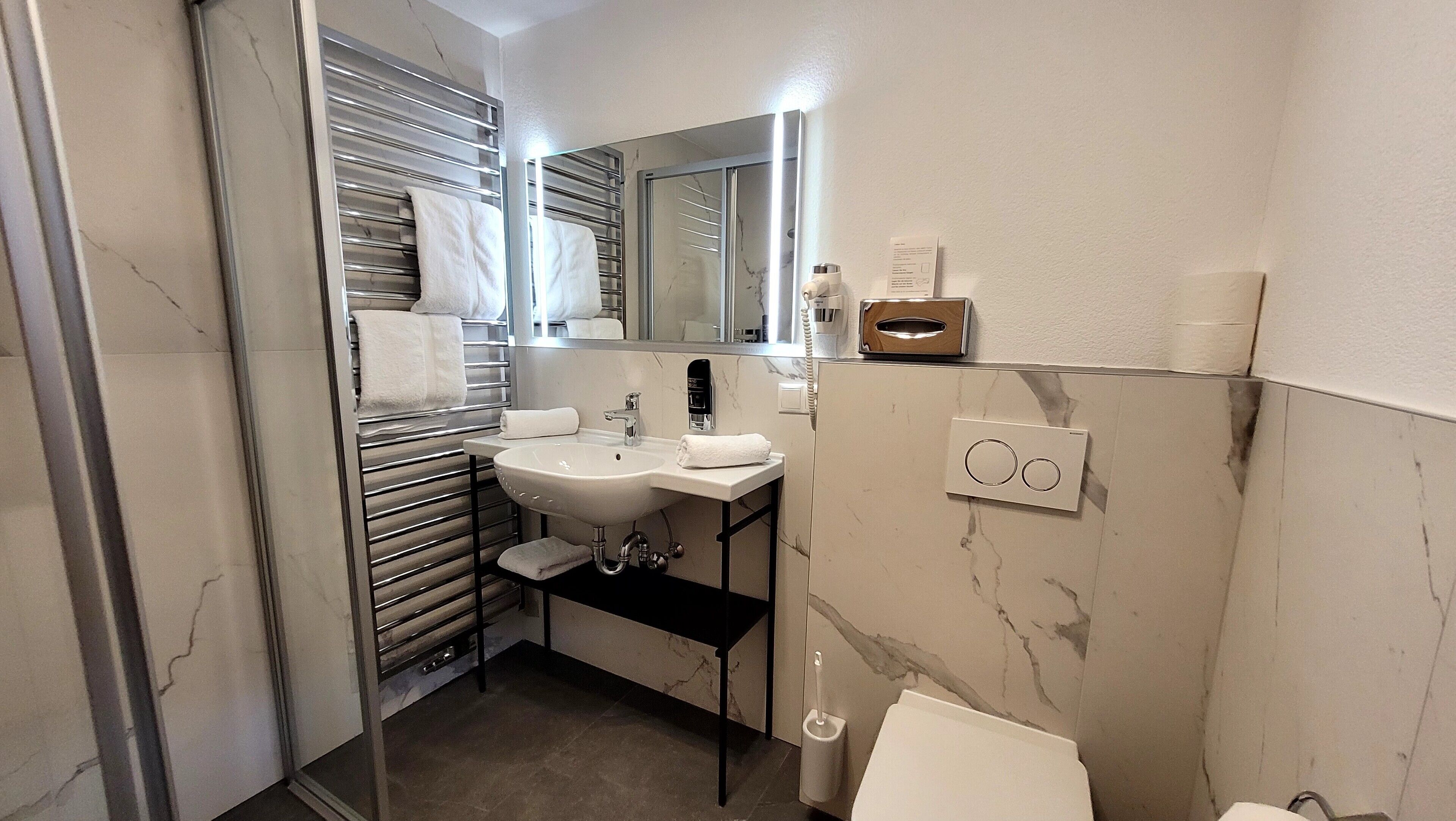 Un baño moderno con cabina de ducha de vidrio, un lavabo blanco y un espejo sobre el lavabo.