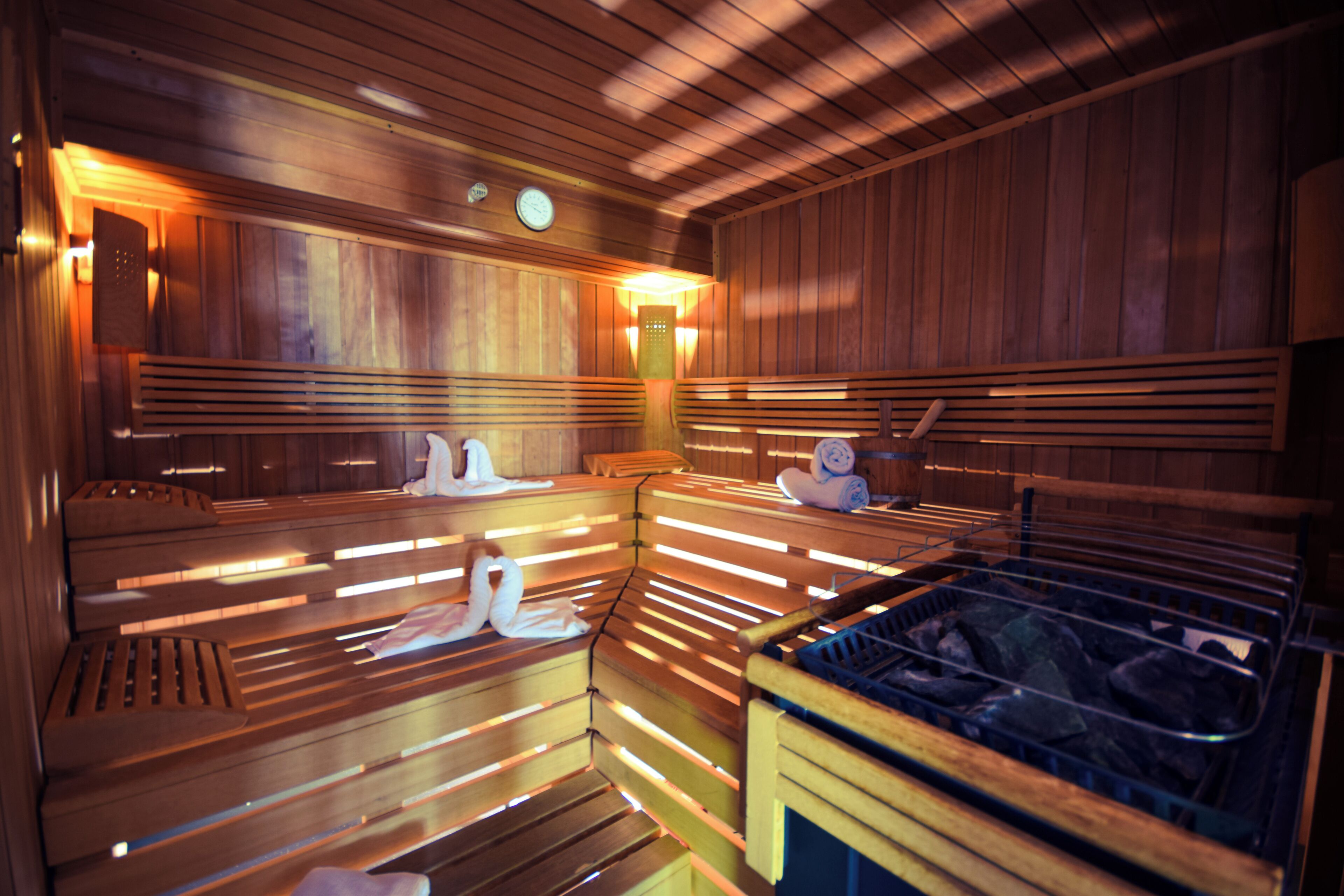 A sauna with wooden benches, a bench with a towel, and a bench with a towel rack.