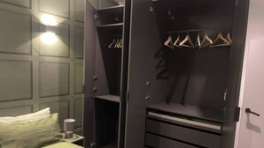 A bedroom with a bed, a bedside table, a wardrobe with hanging space, and a mirror.