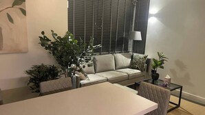 A modern living room with a sofa, a dining table, and potted plants.