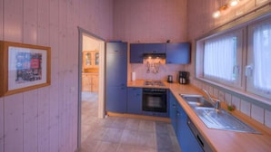 A compact kitchen with wooden cabinets, a stove, and a sink.