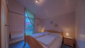 A bedroom with a wooden bed, bedside tables, and a window with curtains.
