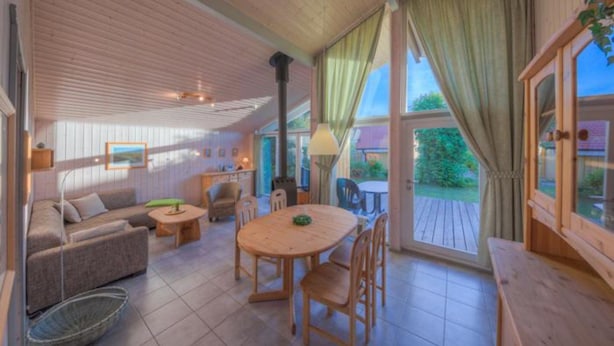 A spacious living area with a wooden ceiling, a round wooden table, and a sofa.