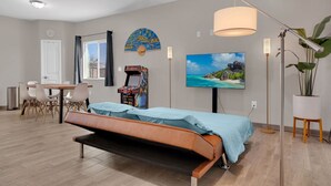 A modern bedroom with a bed, a desk, chairs, a TV, and a large window. - A-Mountain Wonder! HUGE yard, dogs OK - Brand New everything Close to Downtown! (Tucson)