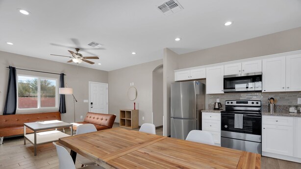 A modern kitchen with white cabinets, stainless steel appliances, and a wooden dining table. - A-Mountain Wonder! HUGE yard, dogs OK - Brand New everything Close to Downtown! (Tucson)
