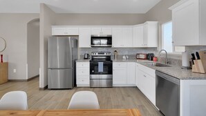 A modern kitchen with white cabinets, stainless steel appliances, granite countertops, and a dishwasher. - A-Mountain Wonder! HUGE yard, dogs OK - Brand New everything Close to Downtown! (Tucson)