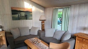 Ein gemütliches Wohnzimmer mit zwei Sofas, einem Holztisch, einem Korbstuhl und einem Schrank.