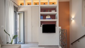 A modern living room with a sofa, a coffee table, a TV mounted on the wall, and a staircase with a railing. - Elegant City Apartment - 250m From Solomos Square (Zakynthos)