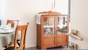 A dining area with a wooden cabinet containing glassware and a white cloth on top. - Elegant City Apartment - 250m From Solomos Square (Zakynthos)