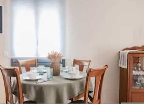 A dining table with a green tablecloth, surrounded by wooden chairs. A vase with dried flowers is placed on the table. - Elegant City Apartment - 250m From Solomos Square (Zakynthos)