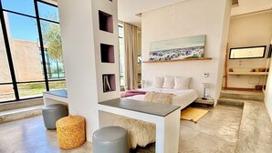 A modern bedroom with a bed, bedside tables, a large window, and a painting on the wall. - Palais Akbal (Marrakech)