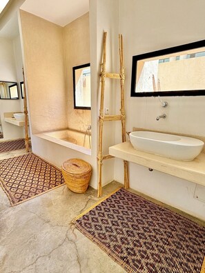 A bathroom with a bathtub, a large mirror, a sink, and a woven ladder. - Palais Akbal (Marrakech)