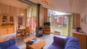 Interior acogedor de una cabaña con detalles de madera, una chimenea, un televisor y un comedor.