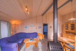 Et interiør af en træhytte med en sofa, et bord og en stor ovn.