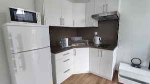 Uma cozinha compacta com armários brancos, micro-ondas, fogão e pia.