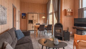 A cozy wooden interior with a sofa, dining table, chairs, a fireplace, and a television. - Ferienhaus im Skandinavischen Stil (Rechlin)