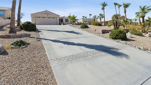 A residential driveway with a garage, palm trees, and a gravel pathway. - Havasu Hacienda Private Pool! (Lake Havasu City)