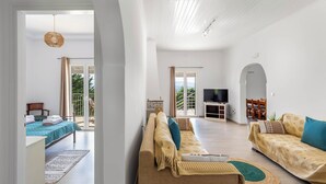 A spacious living area with a sofa, a television, and a balcony with a view.