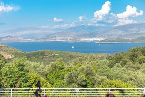 A coastal landscape with a sailboat on the water, hills in the background, and a view of the sea. - Villa Marialetta (Corfu)