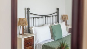 A bedroom with a bed, bedside tables, lamps, and a mirror.