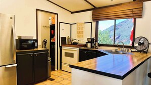 A compact kitchen with a refrigerator, microwave, sink, and a window offering a view of a mountainous landscape. - Oak Creek Viewpoint The Views! (Sedona)