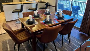 A dining area with a wooden table set for four, surrounded by brown chairs. A kitchen with a sink and a microwave is visible in the background. - Oak Creek Viewpoint The Views! (Sedona)