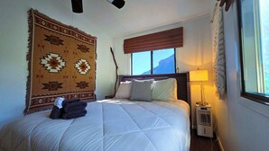 A bedroom with a bed, a large patterned rug, a window with a view, and a bedside table with a lamp. - Oak Creek Viewpoint The Views! (Sedona)