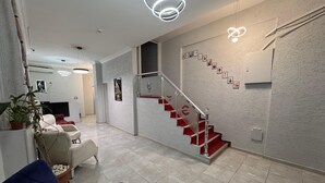 A modern interior with a staircase, a seating area, and a wall-mounted TV. - PENDİK SUİT OTEL (Istanbul)