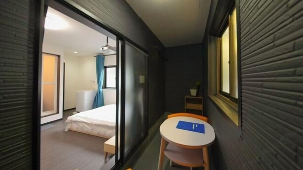 A compact hotel room with a bed, a small table, and a chair. - Osaka Blue House / Disposable Bedding / Four Stops Within an Eight-Minute Walk (Osaka)