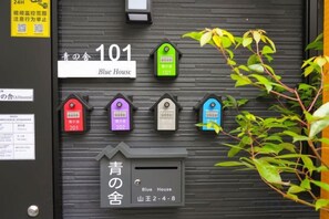 A hotel entrance with a black wall displaying room numbers and a sign for 'Blue House' at 101. - Osaka Blue House / Disposable Bedding / Four Stops Within an Eight-Minute Walk (Osaka)