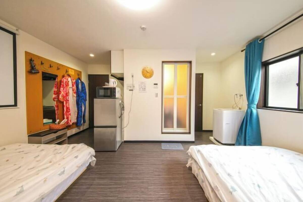 Une chambre d’hôtel avec deux lits, un coin cuisine, un miroir et une vue sur l’extérieur.