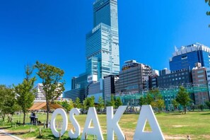 A cityscape with a prominent building and the word 'OSAKA' in the foreground. - Osaka Blue House / Disposable Bedding / Four Stops Within an Eight-Minute Walk (Osaka)