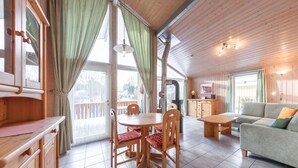 Un intérieur de chalet chaleureux avec un coin repas, un canapé et une cuisine.