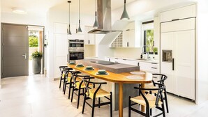 Una cocina moderna con una isla central, luces colgantes y horno empotrado.