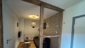 A room with a wooden floor, a bed, a small table with a plant, a hanging light fixture, and a wall-mounted shelf with jars. - World Lodge with unique, city-inspired rooms, located by the forest (Altenau)