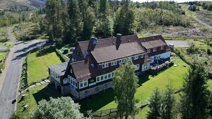 A large, two-story house with a sloped roof, surrounded by a well-maintained lawn and dense trees. - World Lodge with unique, city-inspired rooms, located by the forest (Altenau)