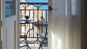 Ein Balkon mit Tisch und Stühlen, der auf ein Gewässer und eine entfernte Insel blickt.