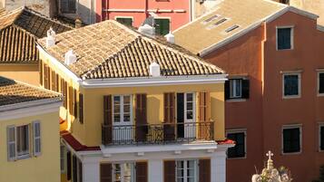Un edificio a più piani con un balcone, persiane rosse e un tetto in tegole.
