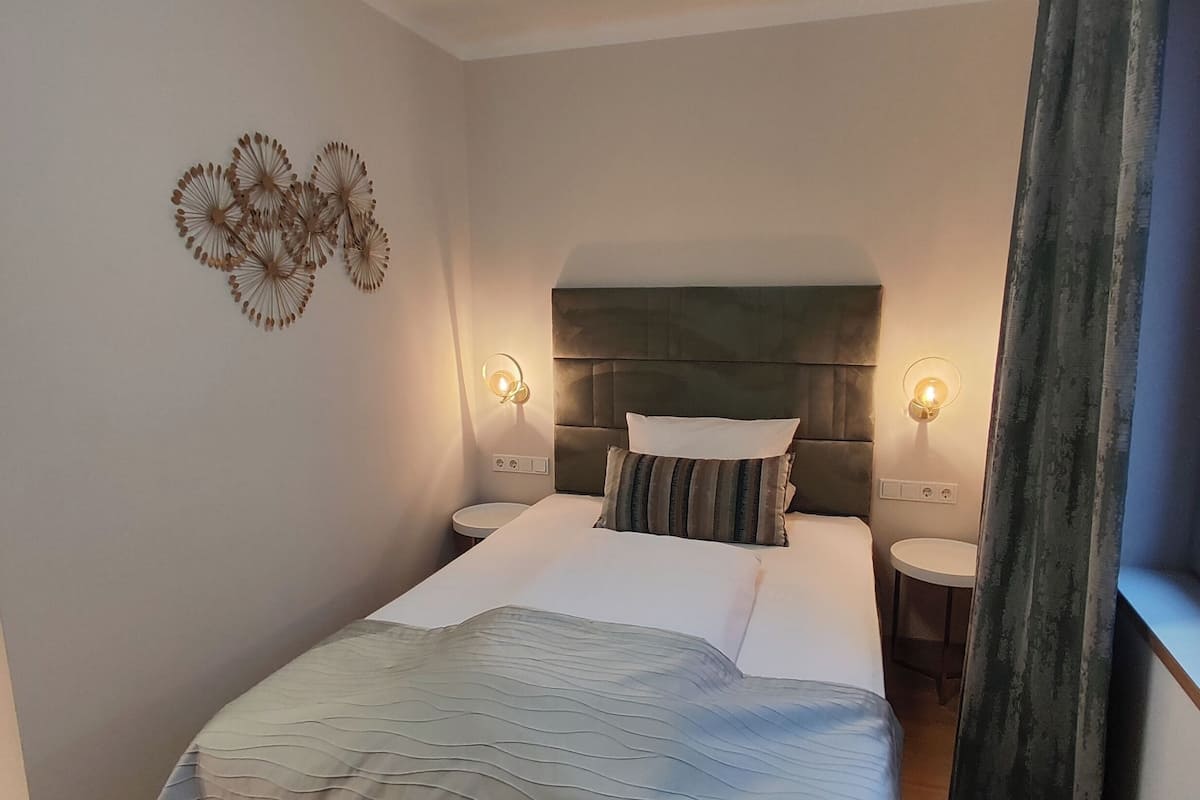 Un dormitorio ordenado con una cama grande, dos mesitas de noche y un cabecero.
