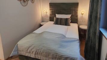 A neatly arranged bedroom with a large bed, two bedside tables, and a headboard.
