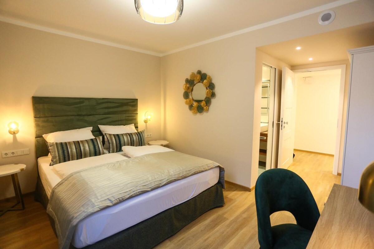 A bedroom with a bed, bedside tables, a wall-mounted light, and a door leading to a closet.