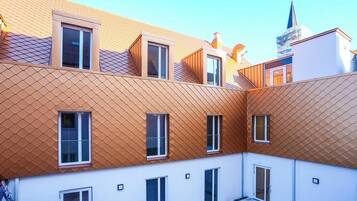 Stylish residential building with balconies and a patterned roof.