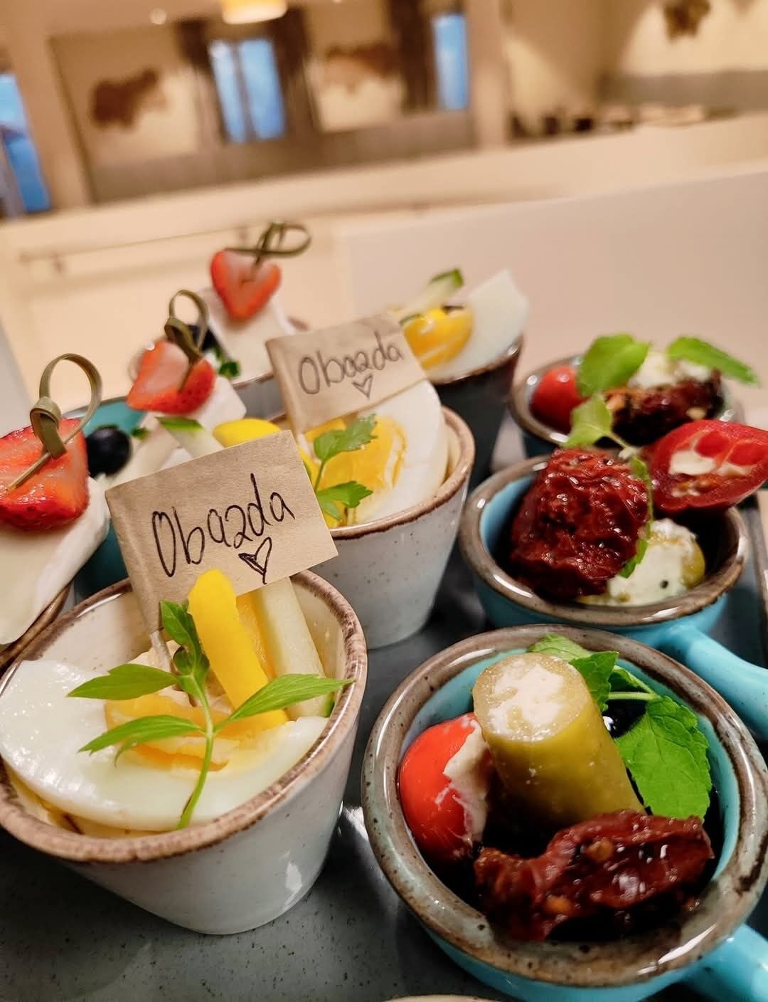 A variety of small bowls with different food items, each labeled with a name tag.
