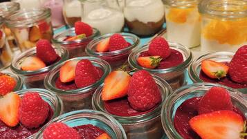 A display of various desserts in glass jars, including strawberry and raspberry toppings.
