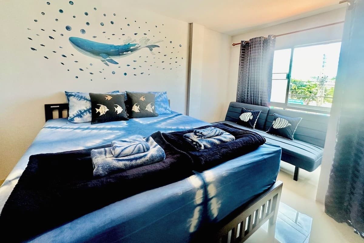 A modern bedroom with a bed, a bench, and a wall mural.
